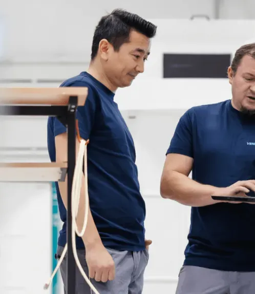 Zwei Vendanor-Techniker testen einen Automaten per Laptop neben dessen Touchscreen und Kartenterminal.