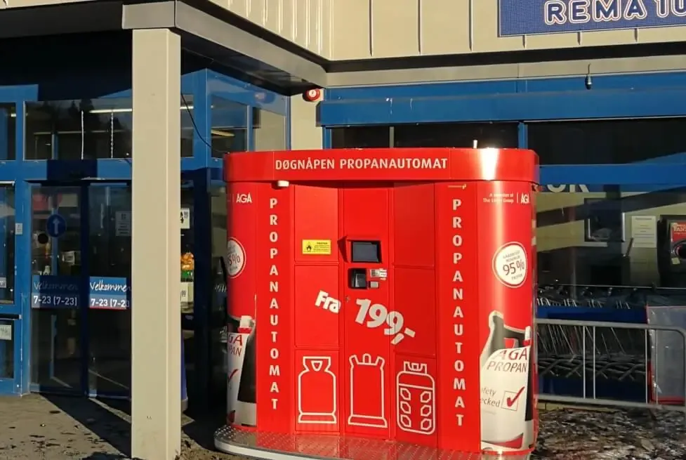 Ein roter AGA-gebrandeter Vendanor Gasflaschenautomat an einem Ladeneingang in Norwegen.