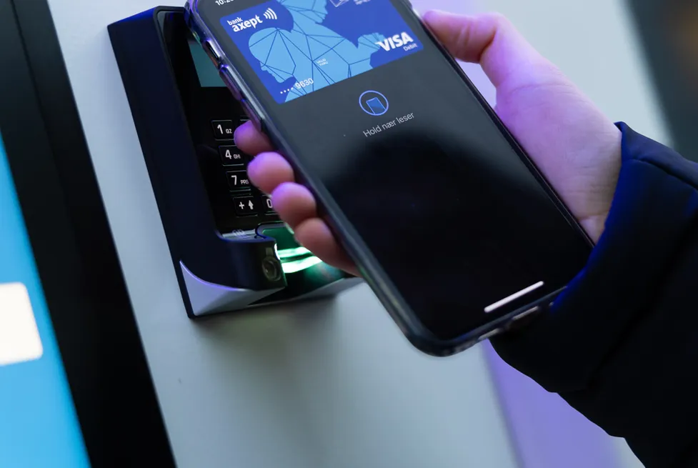 Eine Hand zahlt kontaktlos per Smartphone am Kartenterminal eines Vendanor-Automaten.