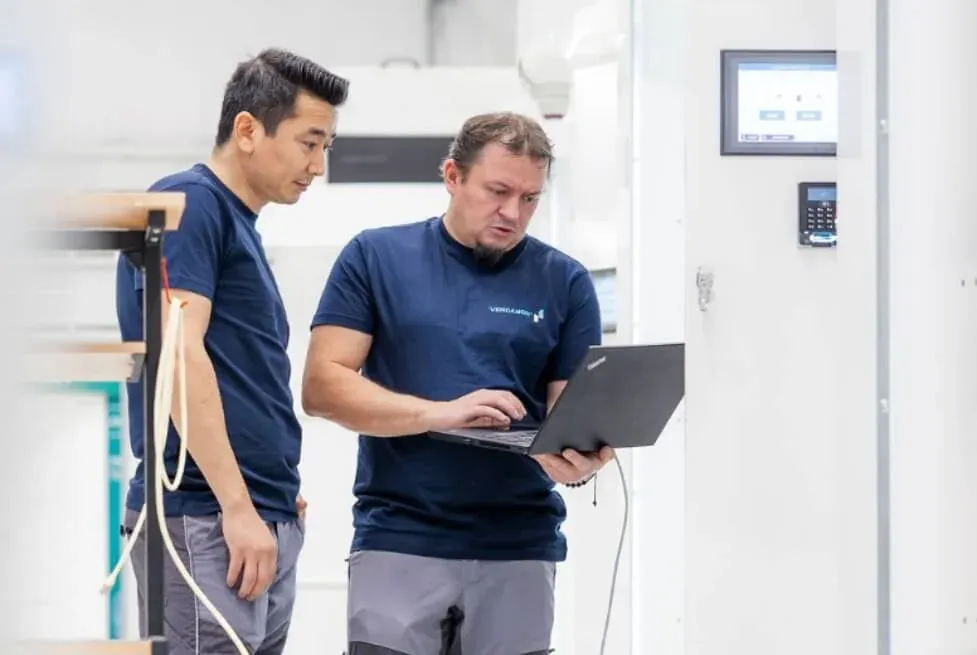 Zwei Vendanor-Techniker führen mit einem Laptop die Endkontrolle eines Gasflaschenautomaten in der Werkstatt durch.