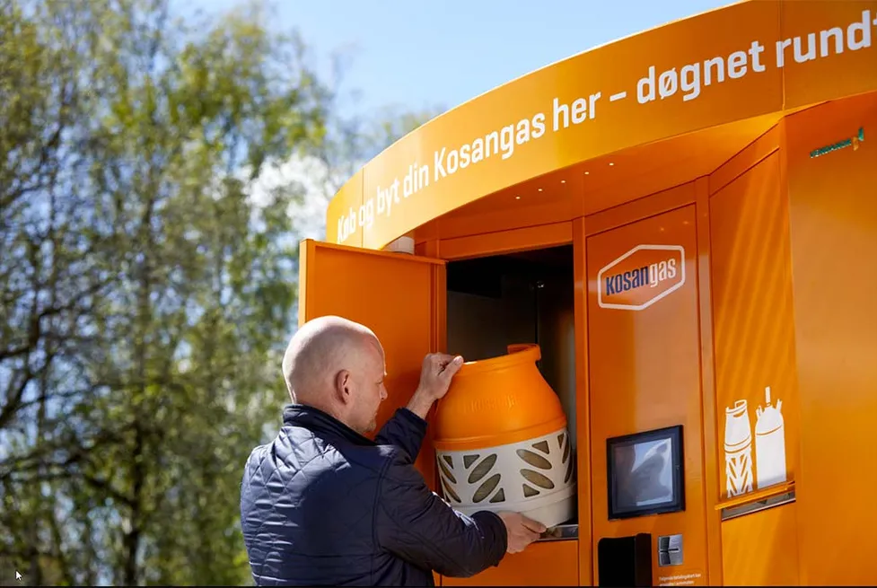 Ein Mann tauscht eine orangefarbene Kosangas-Propangasflasche an einem Vendanor Gasflaschenautomat im Freien.