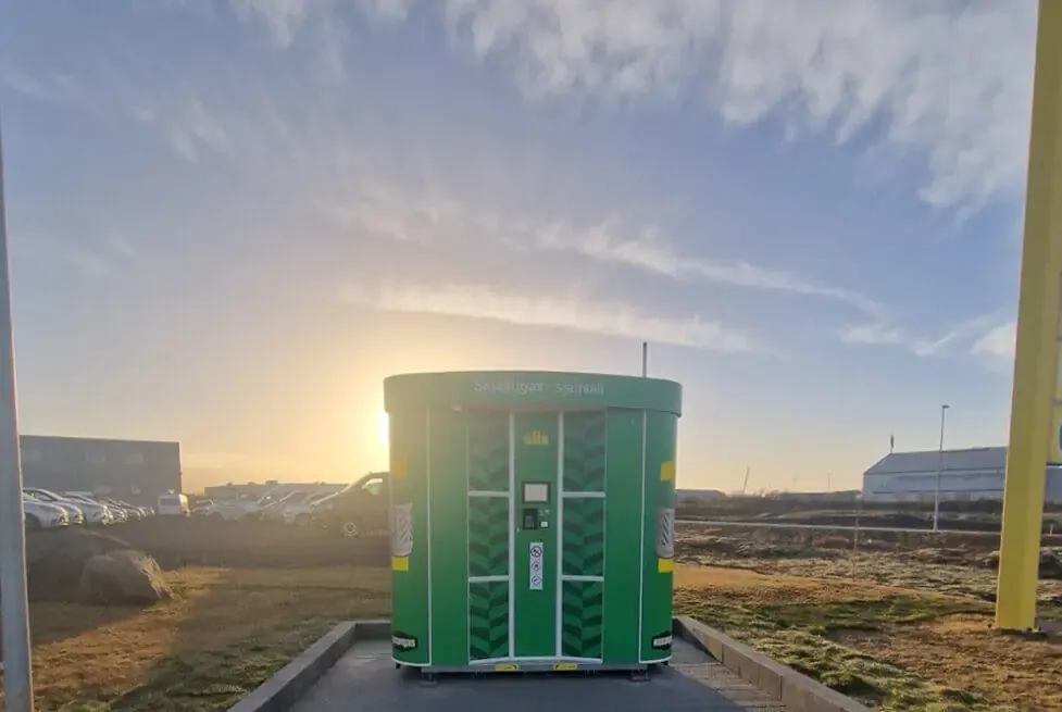 Grüner Vendanor Gasflaschenautomat im Olis-Design im Freien bei Sonnenuntergang.