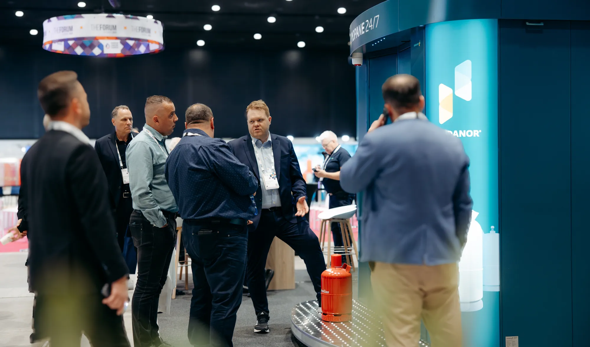 Besøkende samler seg rundt en blågrønn Vendanor Propanautomat på en messestand, med en propanflaske utstilt.