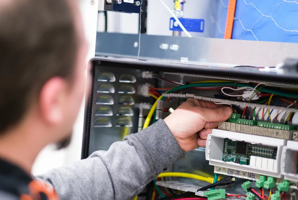 En Vendanor-tekniker arbeider med elektronikken og kablingen inne i en automat under produksjon.