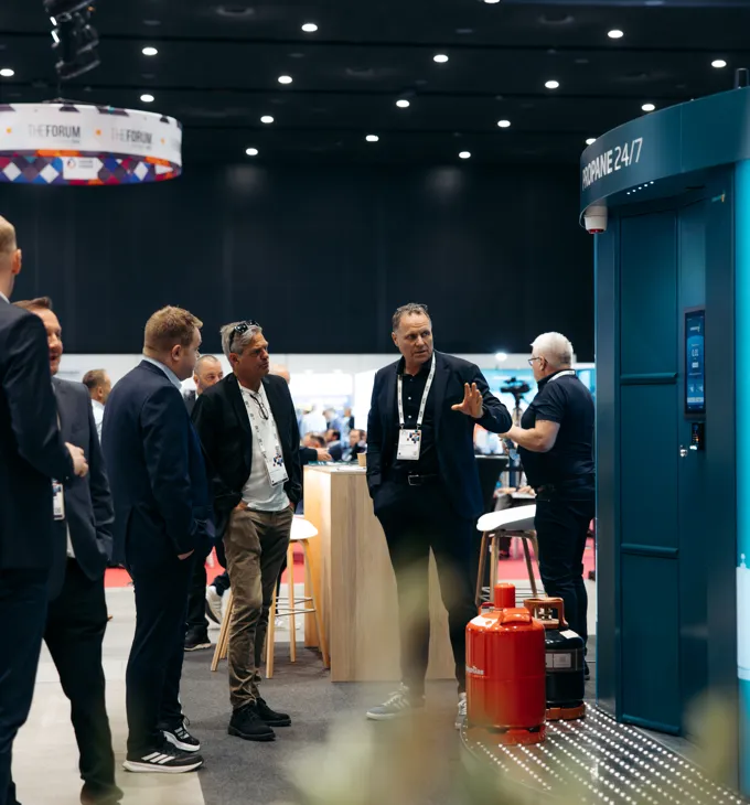Visitors with lanyards talking at the Vendanor stand during a trade fair.